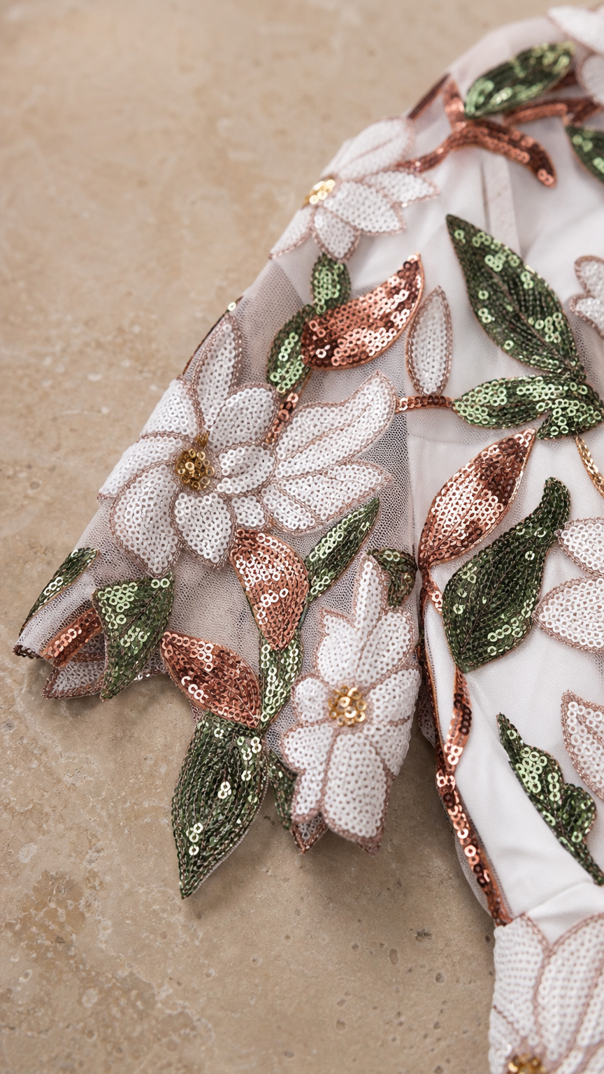 Close-up detail of white mesh fabric with floral embroidery and sequins