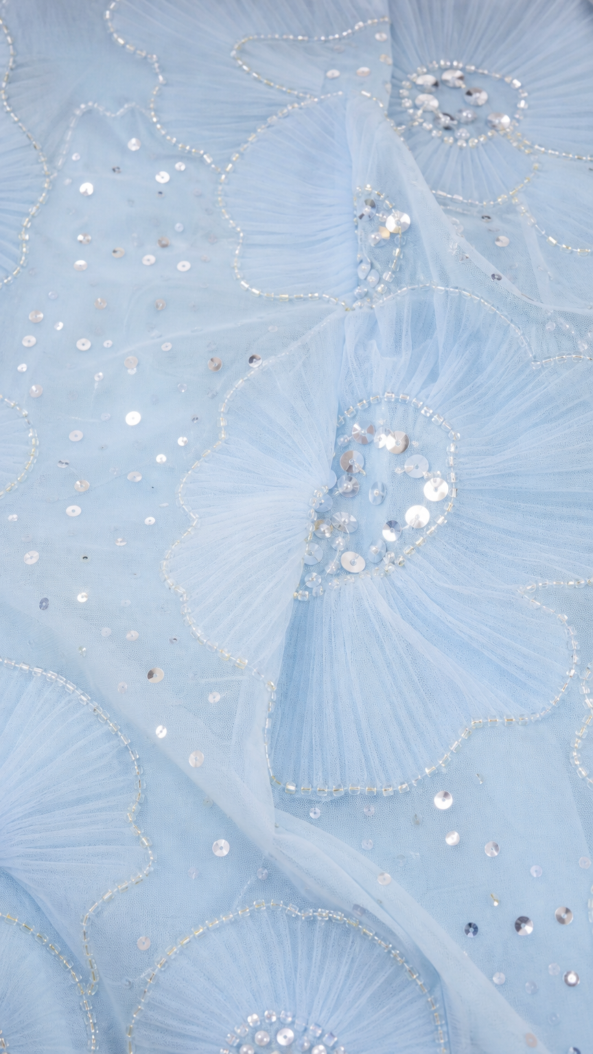Close-up of light blue mesh fabric with sequin floral embroidery