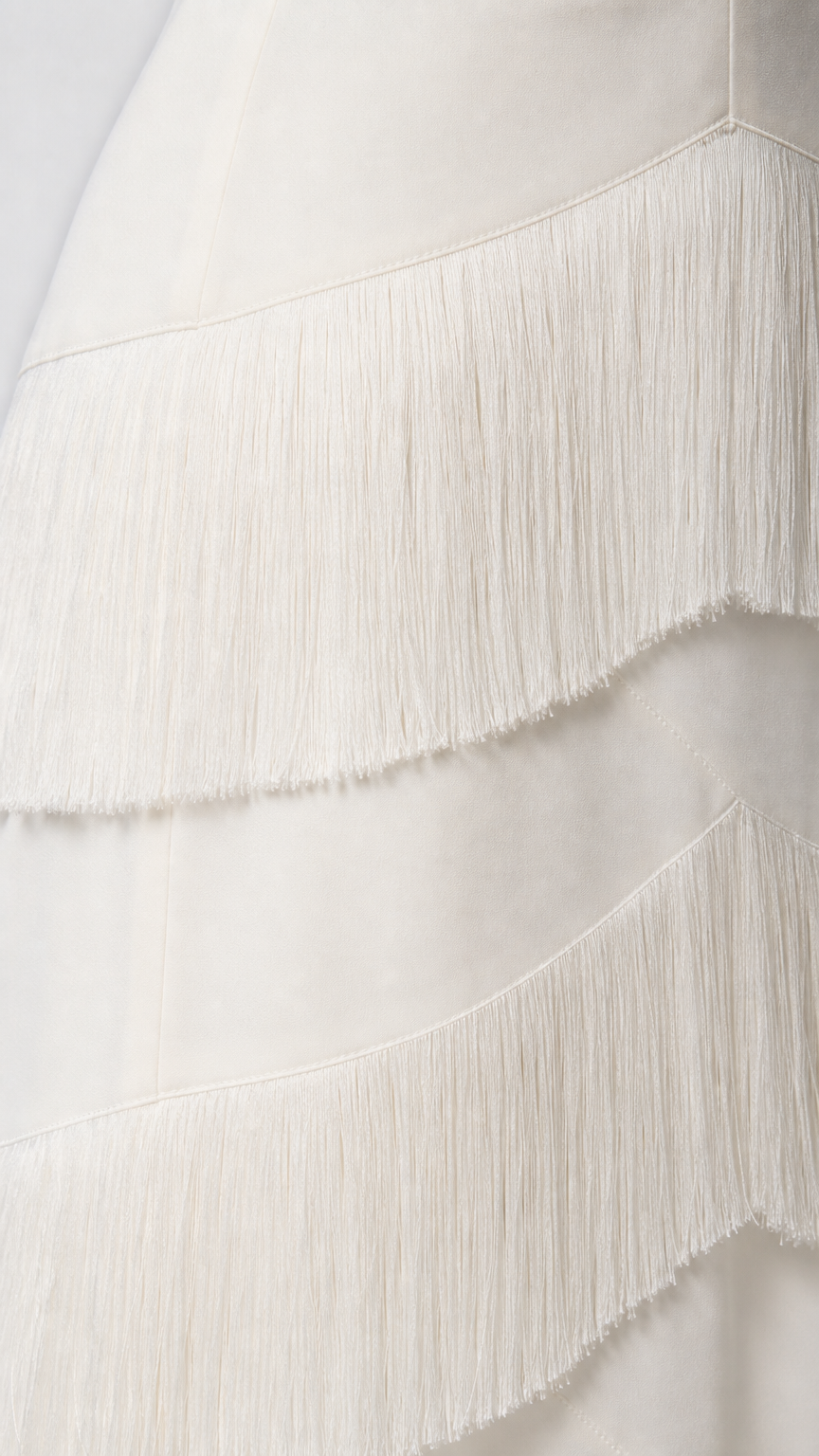 Close-up detail of the fringe texture on the white dress
