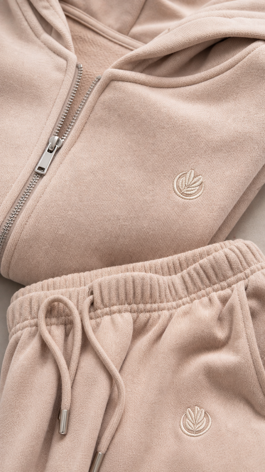 Close-up of beige hoodie zipper, hood, tonal detail, and drawstring pants