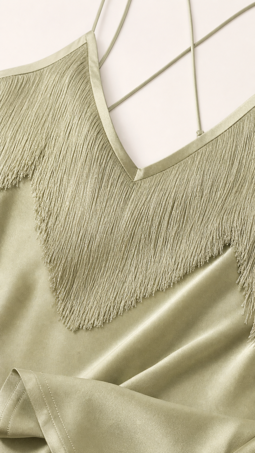Close-up detail of V-neckline, fringe trim, and delicate straps