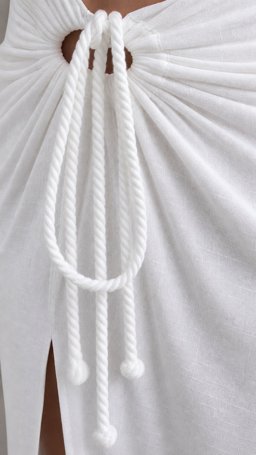 Close-up of decorative rope tie detail on white skirt