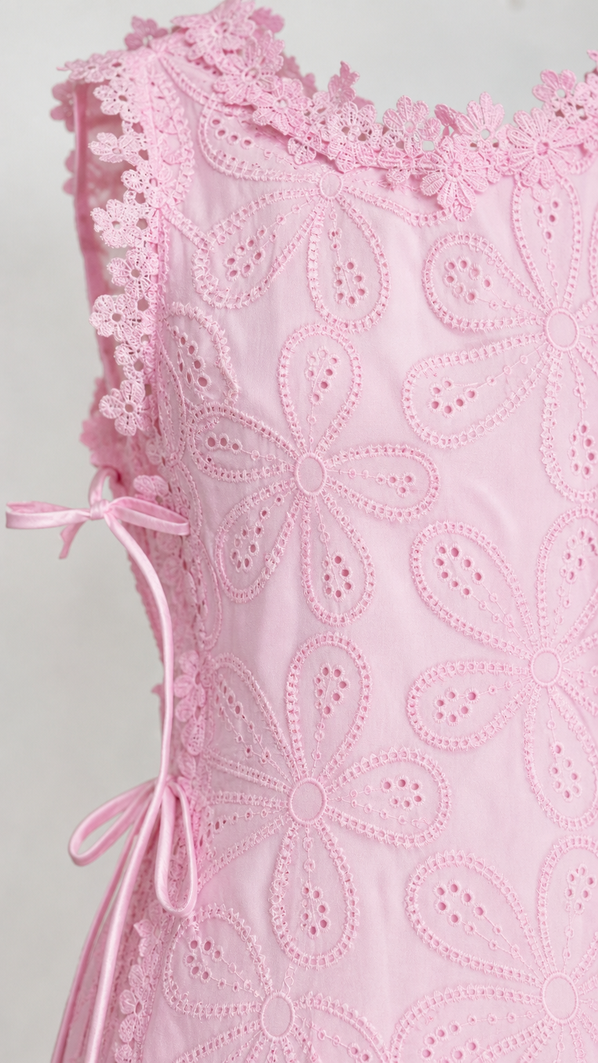 Close-up detail of pink floral eyelet fabric and side tie
