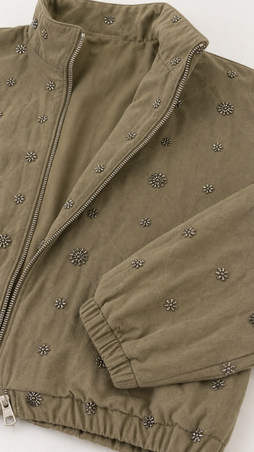 Close-up detail of floral metal studs, zipper, and fabric texture on Olive Green jacket