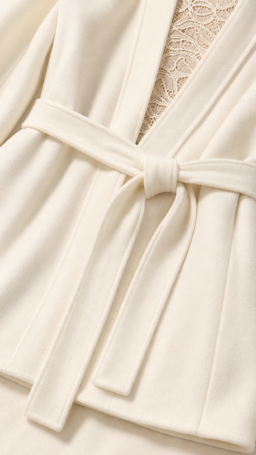 Close-up detail of cream blazer fabric, waist belt knot, and lace underlay