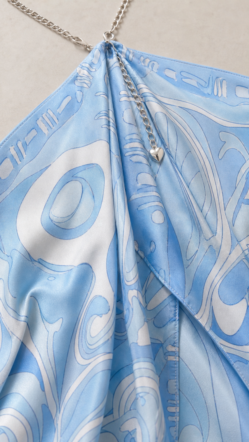 Close-up of sky blue abstract print fabric and metallic chain halter detail
