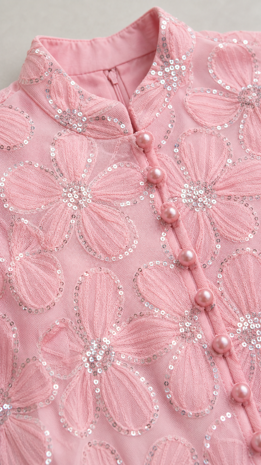 Close-up detail of mock neck, buttons, and sequin floral embroidery