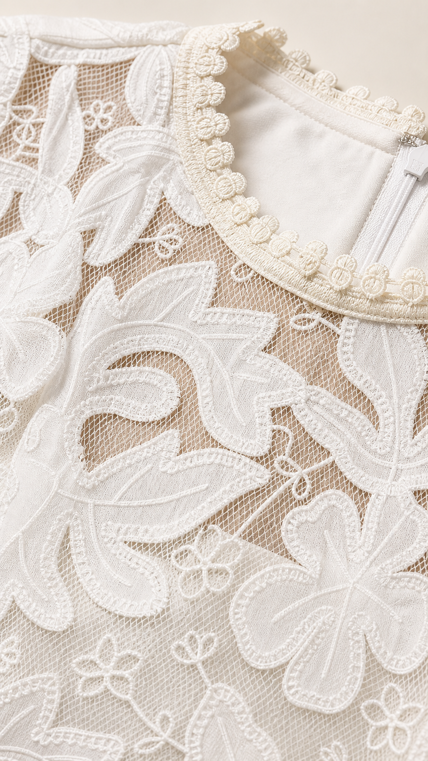 Close-up detail of white floral embroidery and beaded pearl-like trim along the neckline
