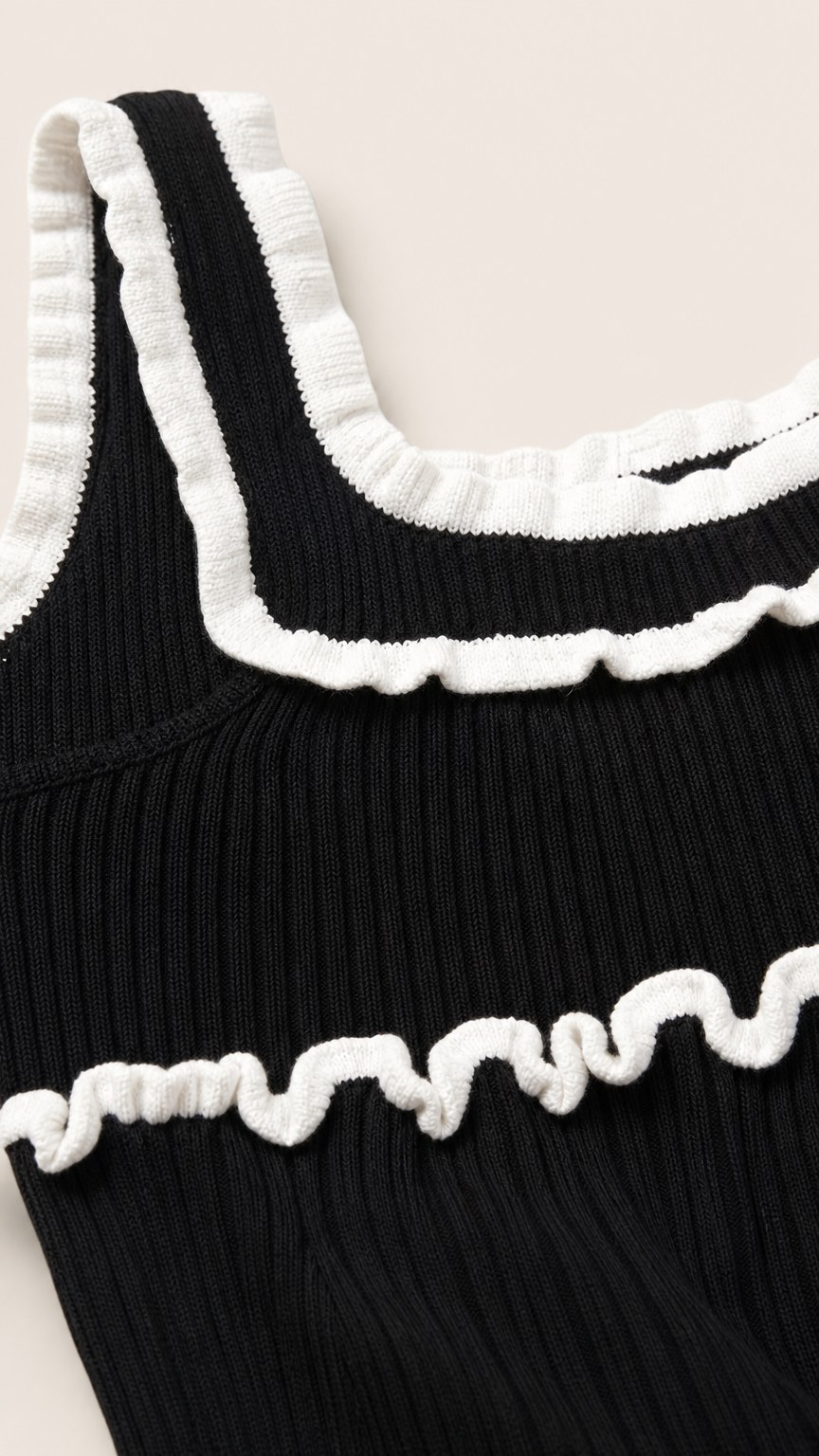 Close-up detail of white lettuce ruffles on black knit top
