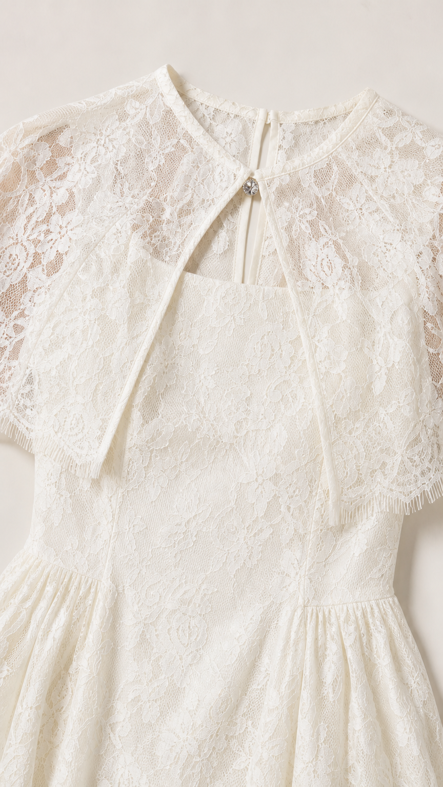 Close up view of delicate ivory lace fabric and capelet keyhole detail