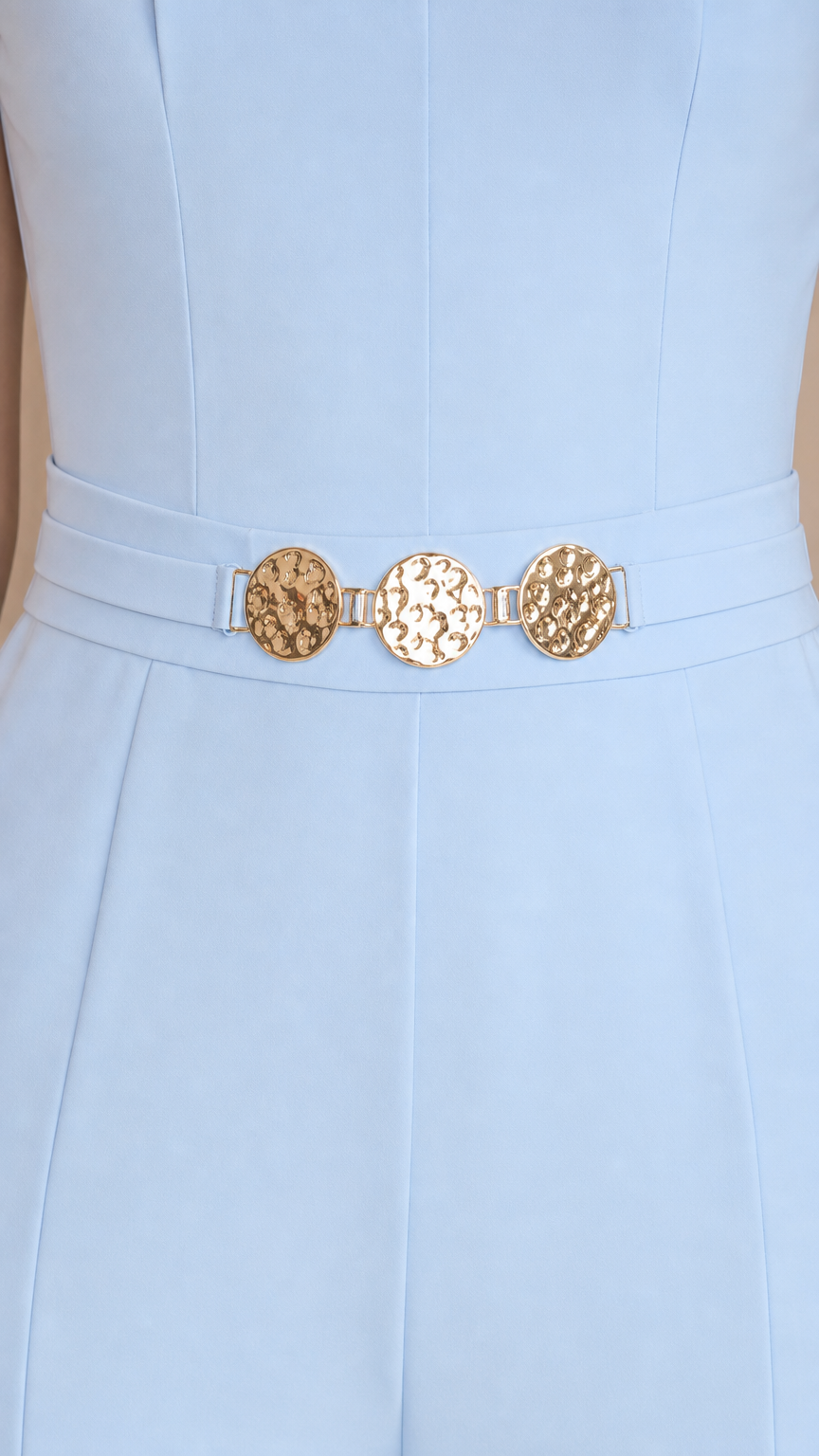 Close-up of metallic gold hardware belt detail on light blue jumpsuit