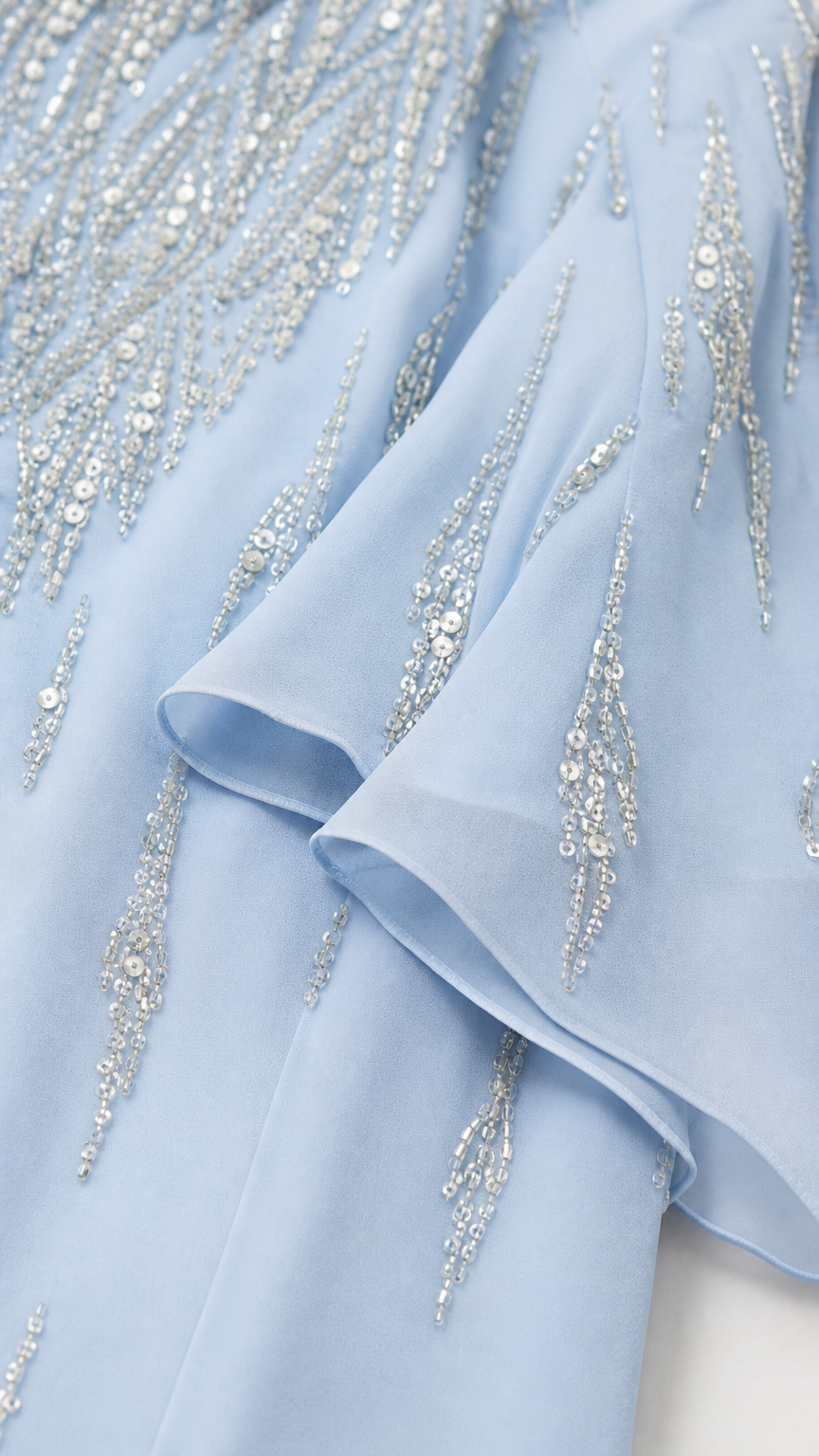 Close-up detail of light blue fabric beadwork and ruffles