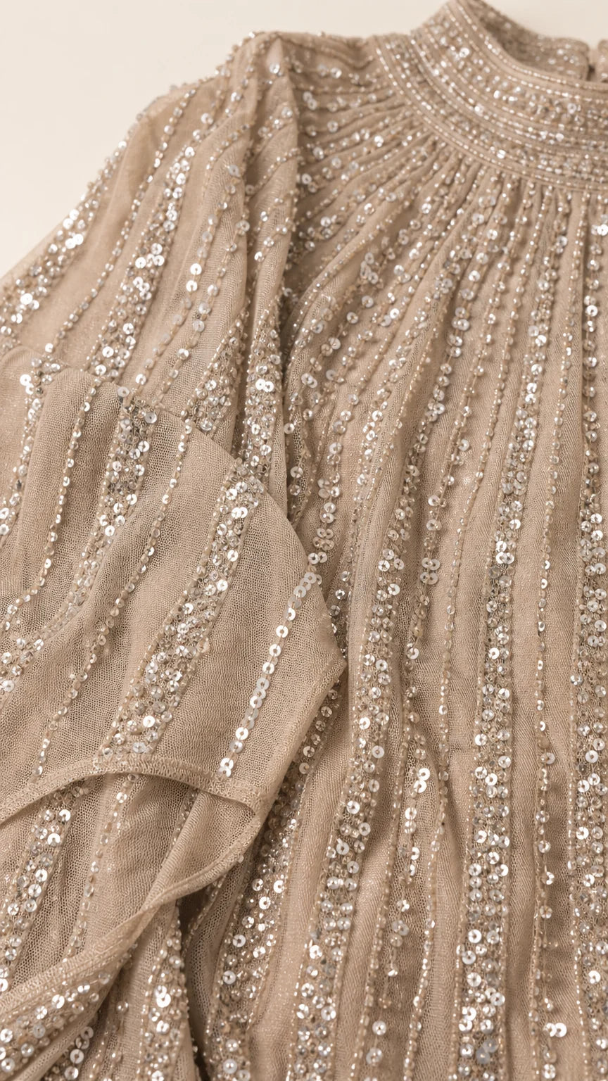 Close-up detail of champagne pleated mesh fabric with linear sequin stripes