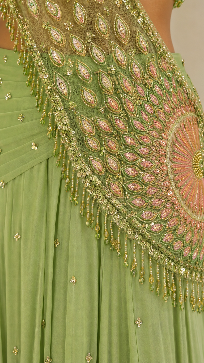 Close-up detail of intricate beadwork, sequins, and hanging fringe on green drape
