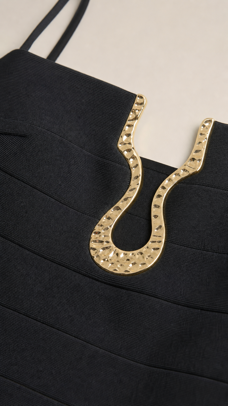 Close-up of gold neckline hardware detail on black dress