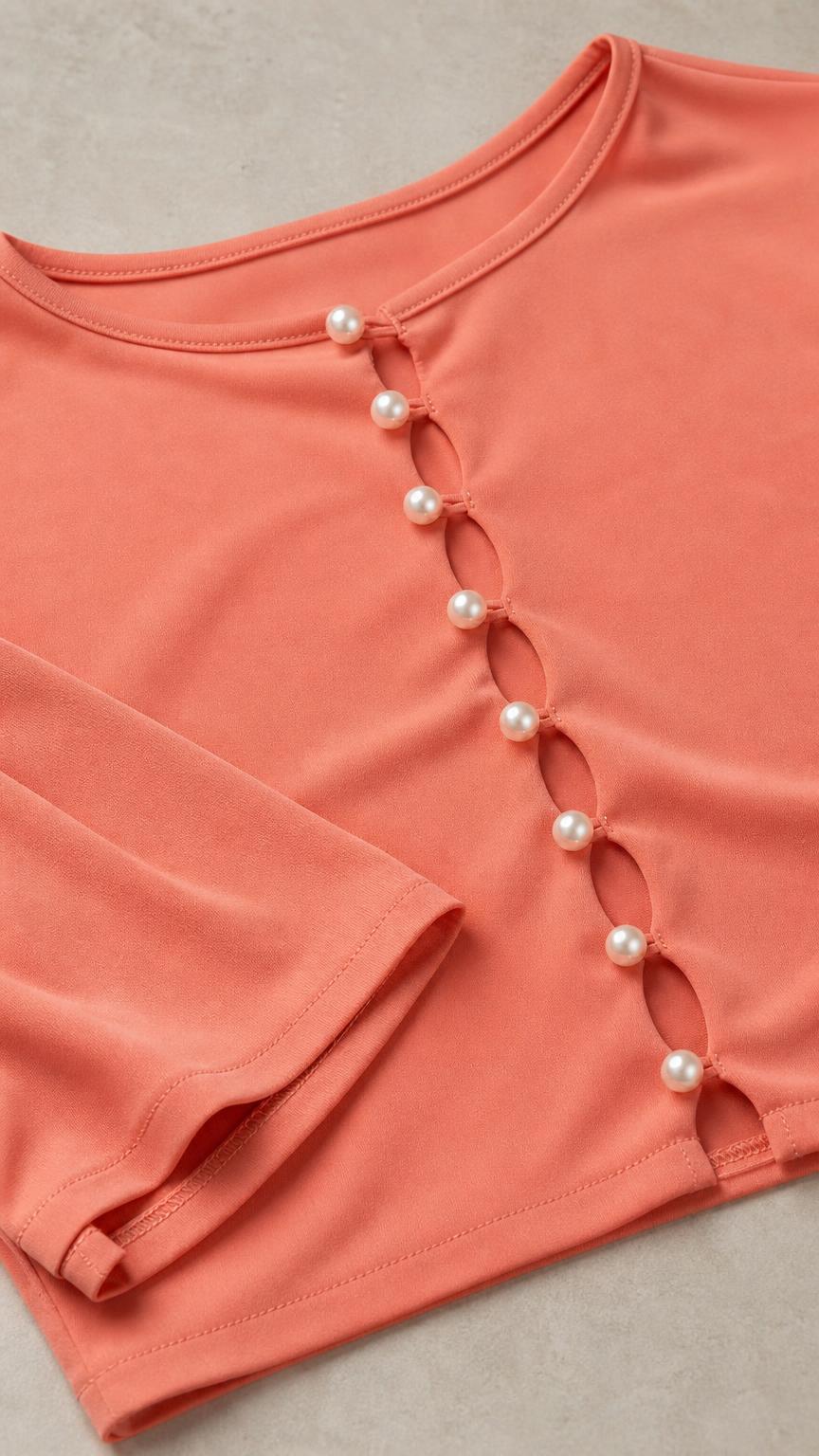 Close-up detail of faux-pearl buttons on peach crop top