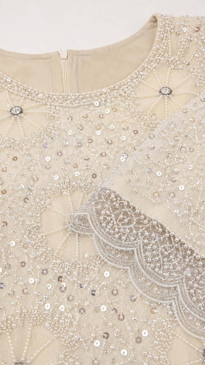 Close-up detail of intricate beading, sequins, and scalloped trim on Champagne neckline and cuff