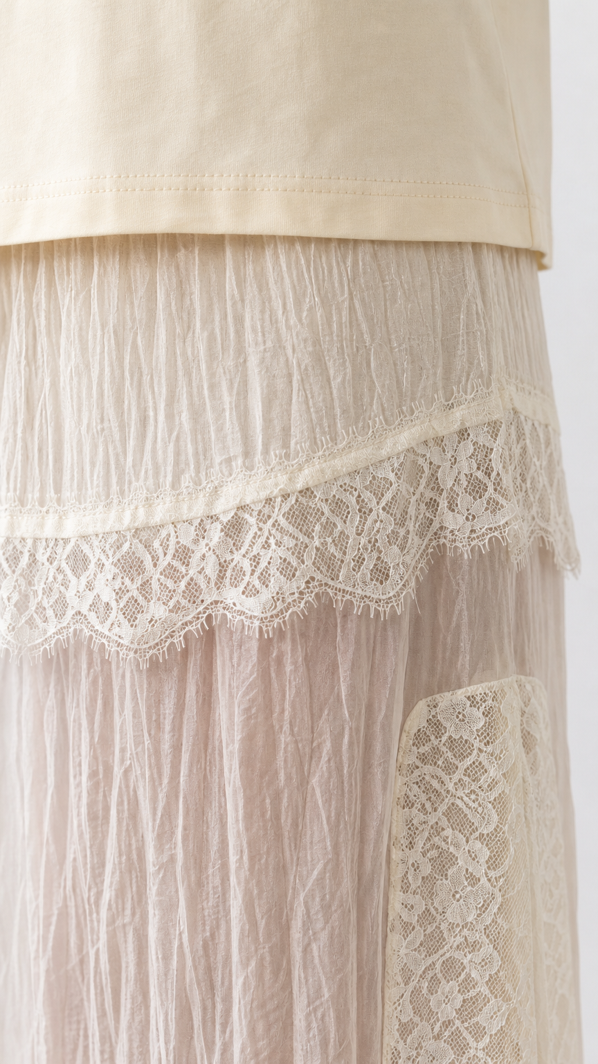 Close-up detail of lace trim and crinkled texture on cream skirt