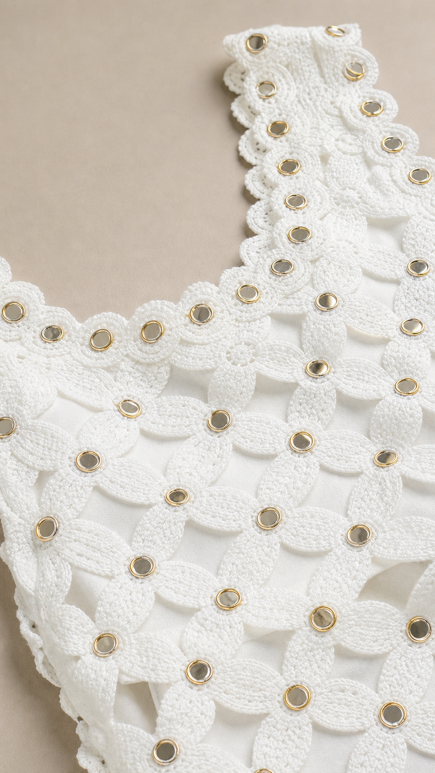 Close-up detail of white crochet neckline with metallic grommets