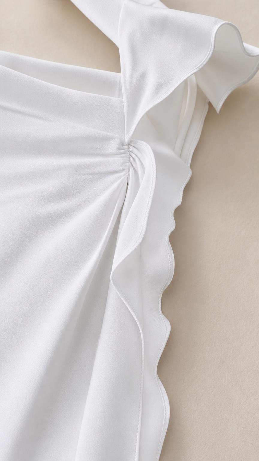 Close-up detail of shoulder strap and side ruffles on white dress