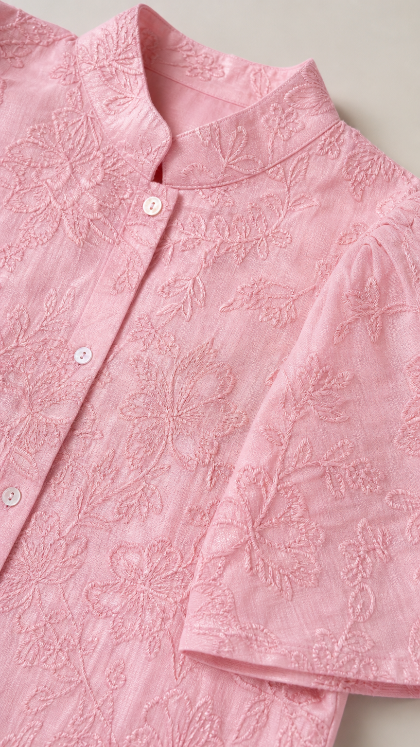 Close-up detail of pink stand collar and intricate floral embroidery on short-sleeve shirt
