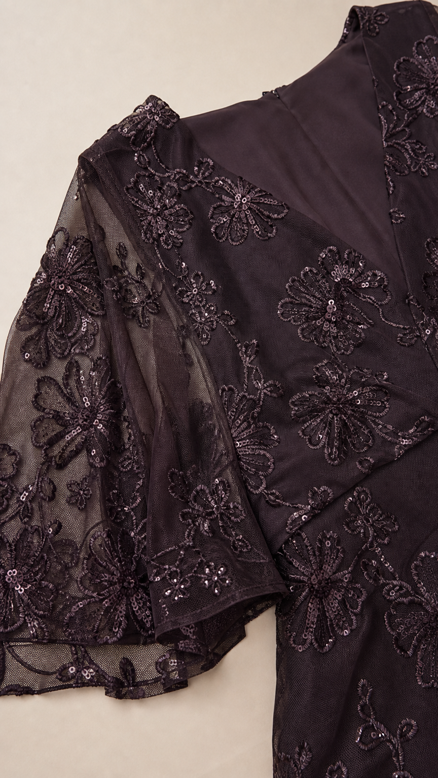 Close-up detail of floral sequin embroidery and sheer flutter sleeve on dark plum gown