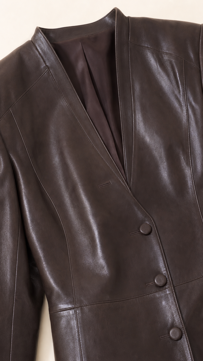 Close-up detail of collarless V-neckline and button closure on Chocolate Brown faux leather blazer