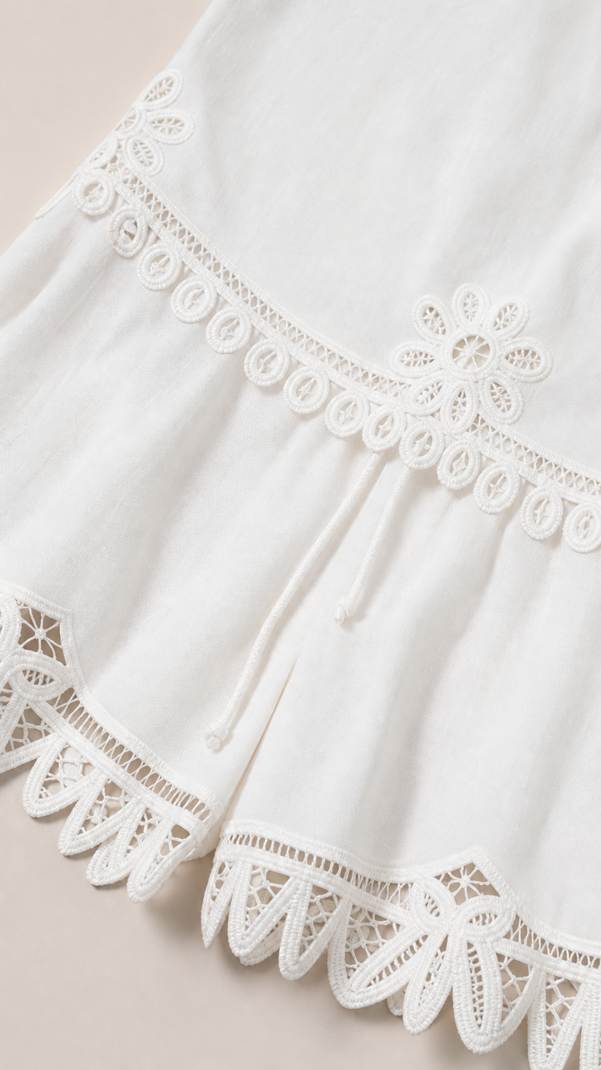 Close-up detail of embroidery and lace hem on white shorts