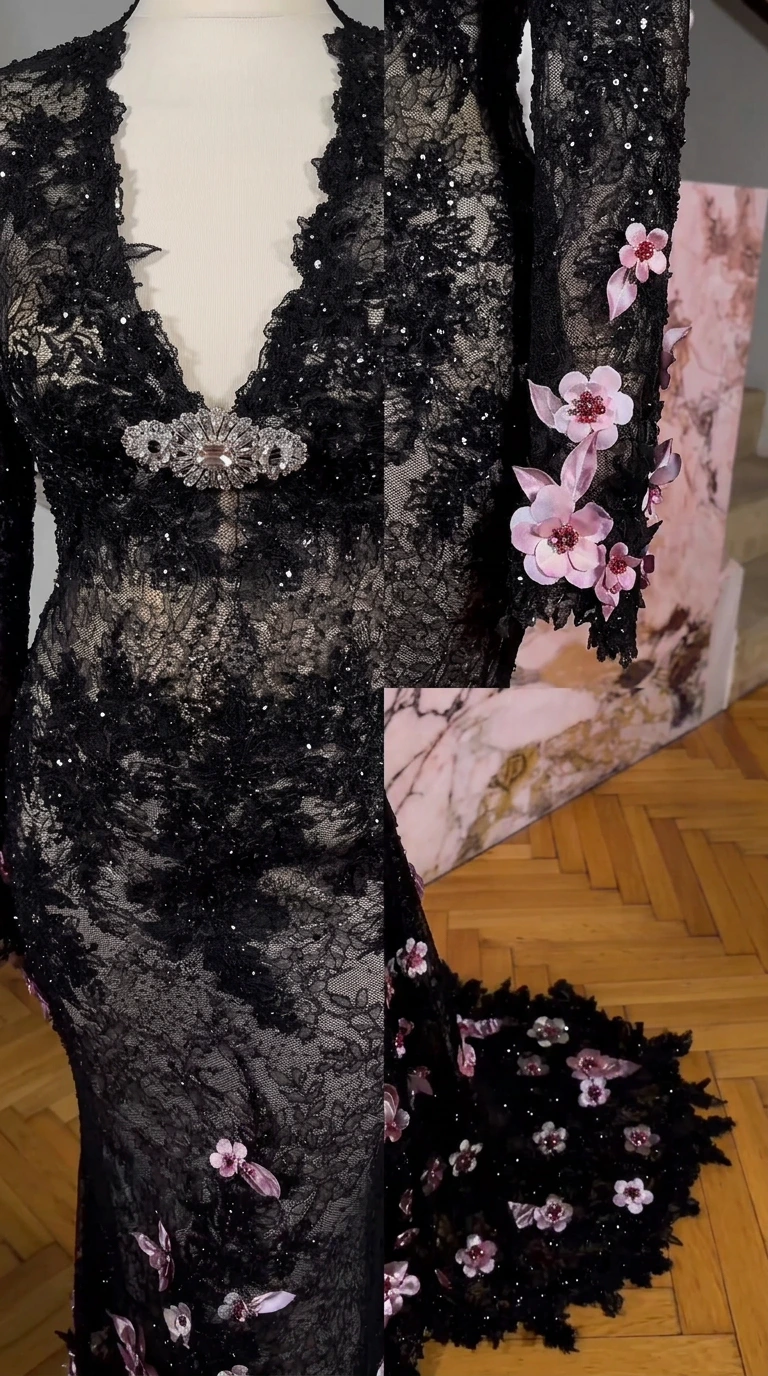 Close up of deep V-neckline, crystal brooch, and 3D flower cuff appliques on black lace dress