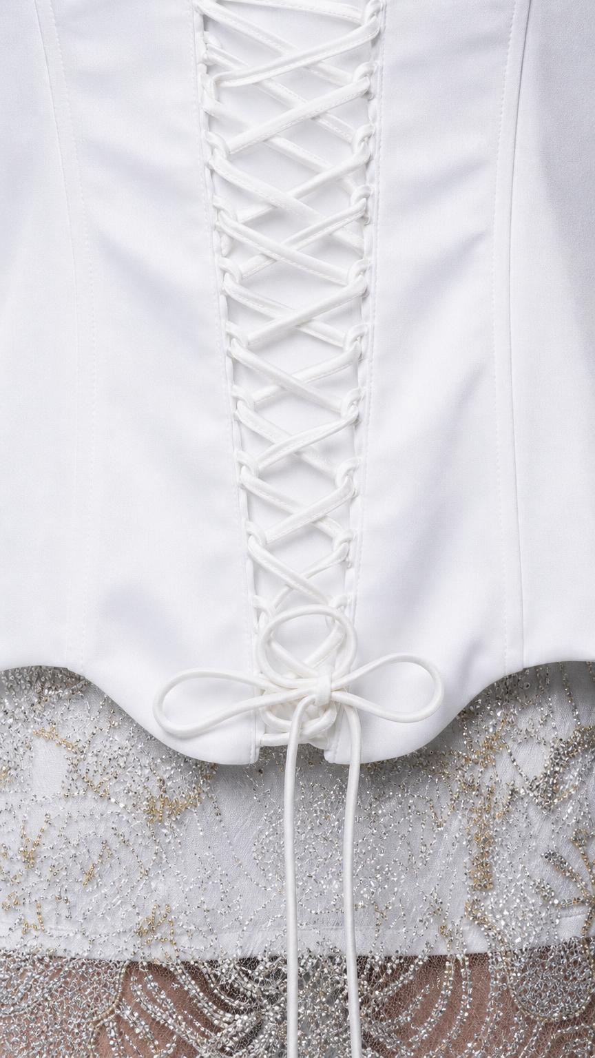 Close-up detail of white lace-up corset back and lace skirt hem