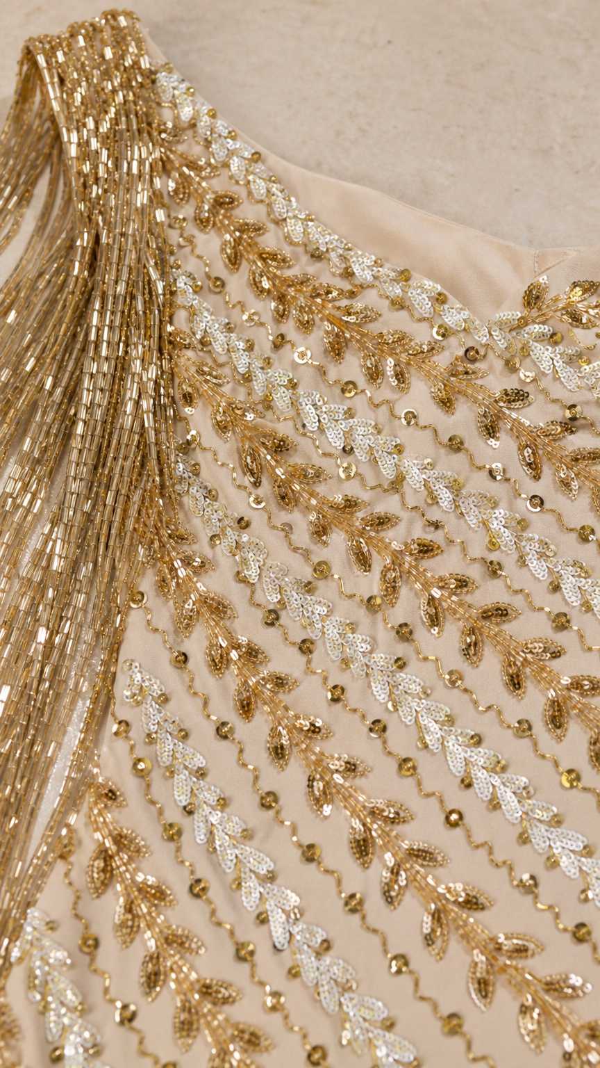 Close-up detail of intricate gold sequin and bead embroidery with fine fringe