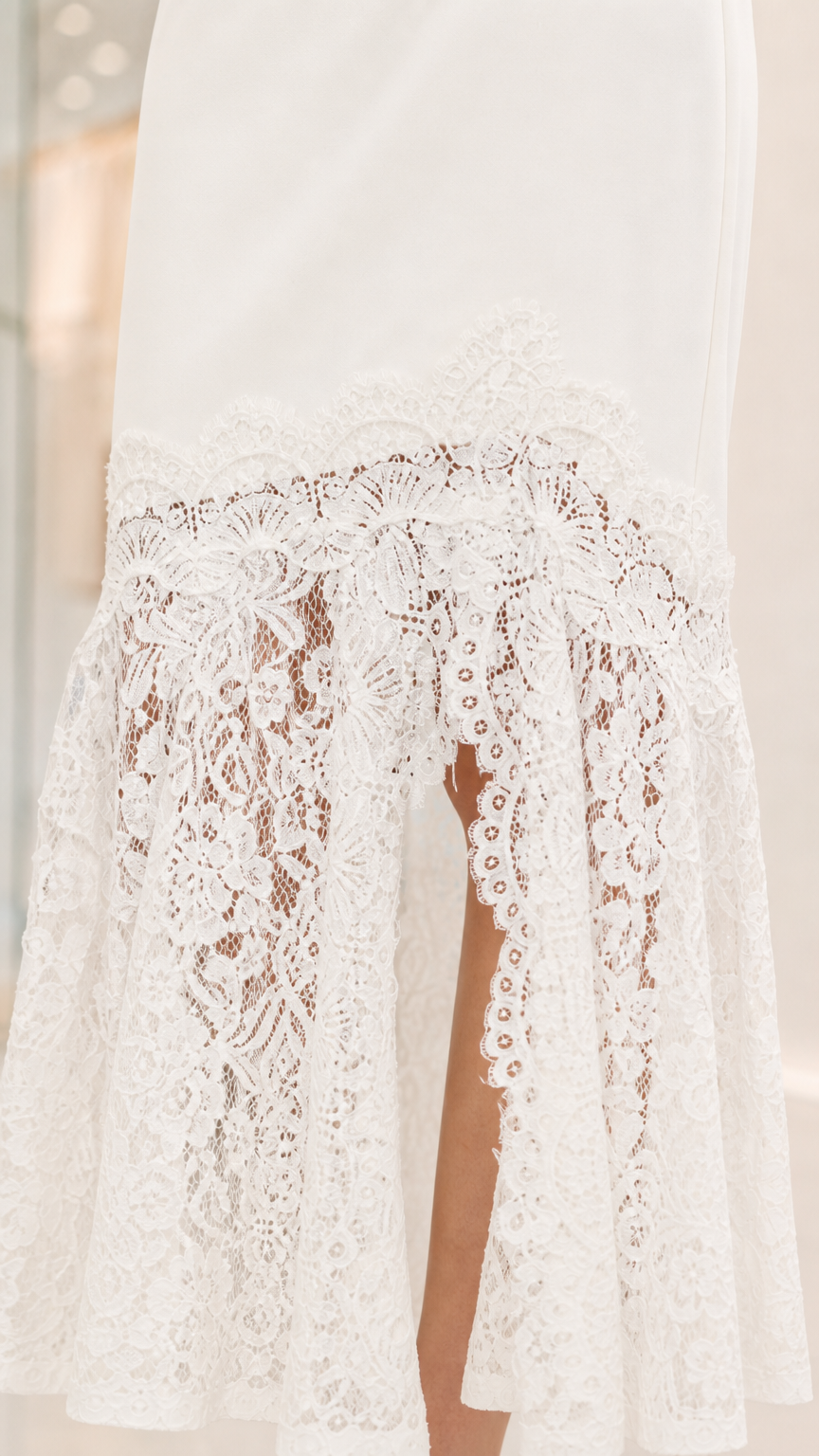 Close up view of the intricate white sheer floral lace hem with side split detail