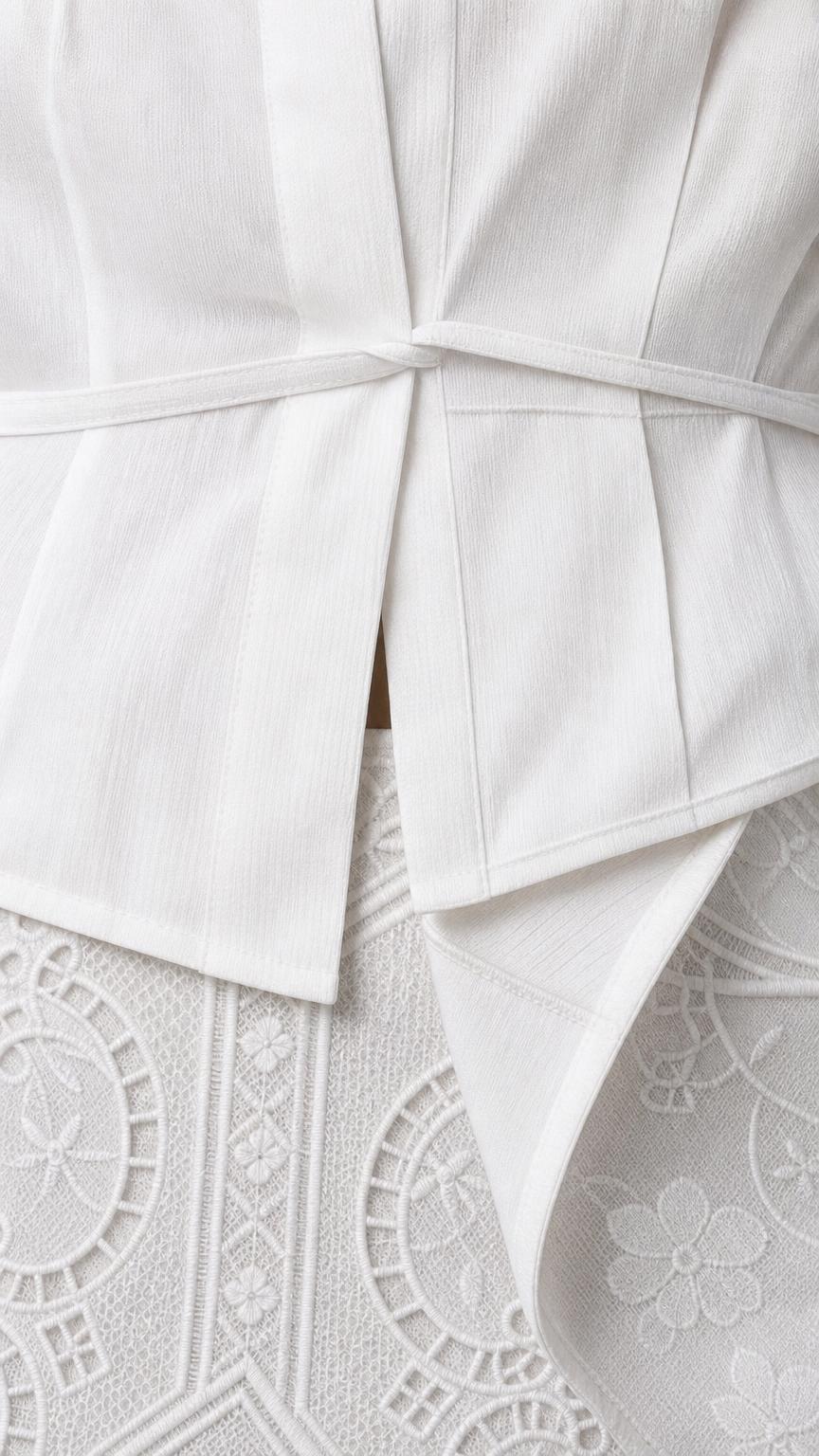 Close-up detail of white peplum top waist and textured skirt pattern
