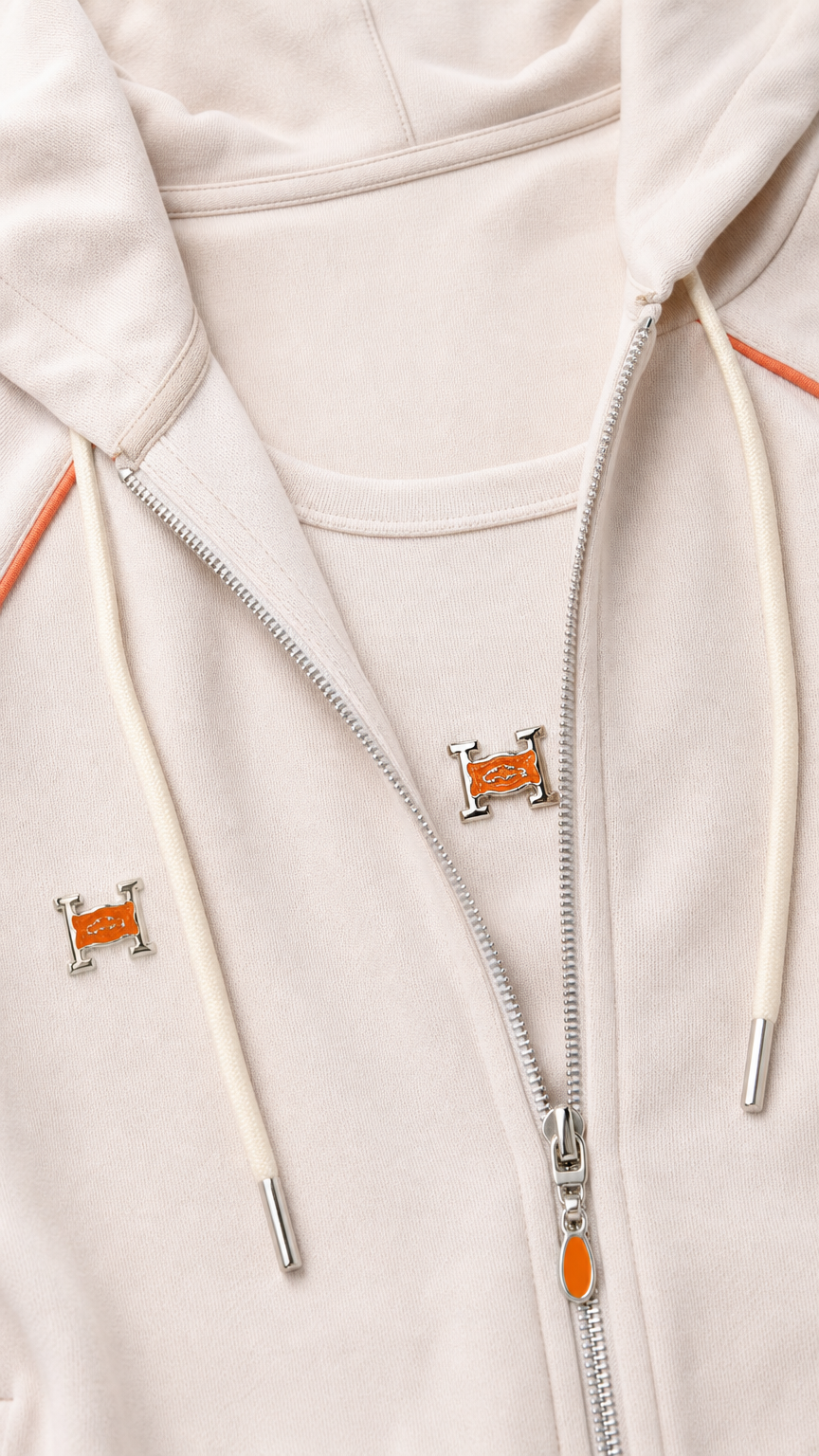 Close-up detail of beige zip hoodie with contrast orange piping and metallic zipper hardware
