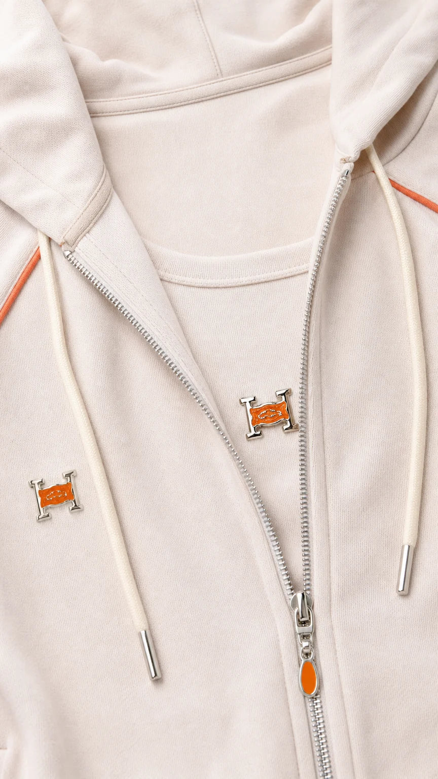 Close-up detail of beige zip hoodie with contrast orange piping and metallic zipper hardware