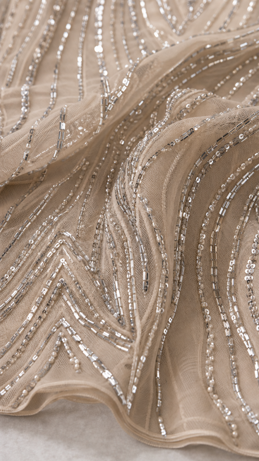Close-up detail of geometric silver sequin and bead embroidery on sheer mesh fabric