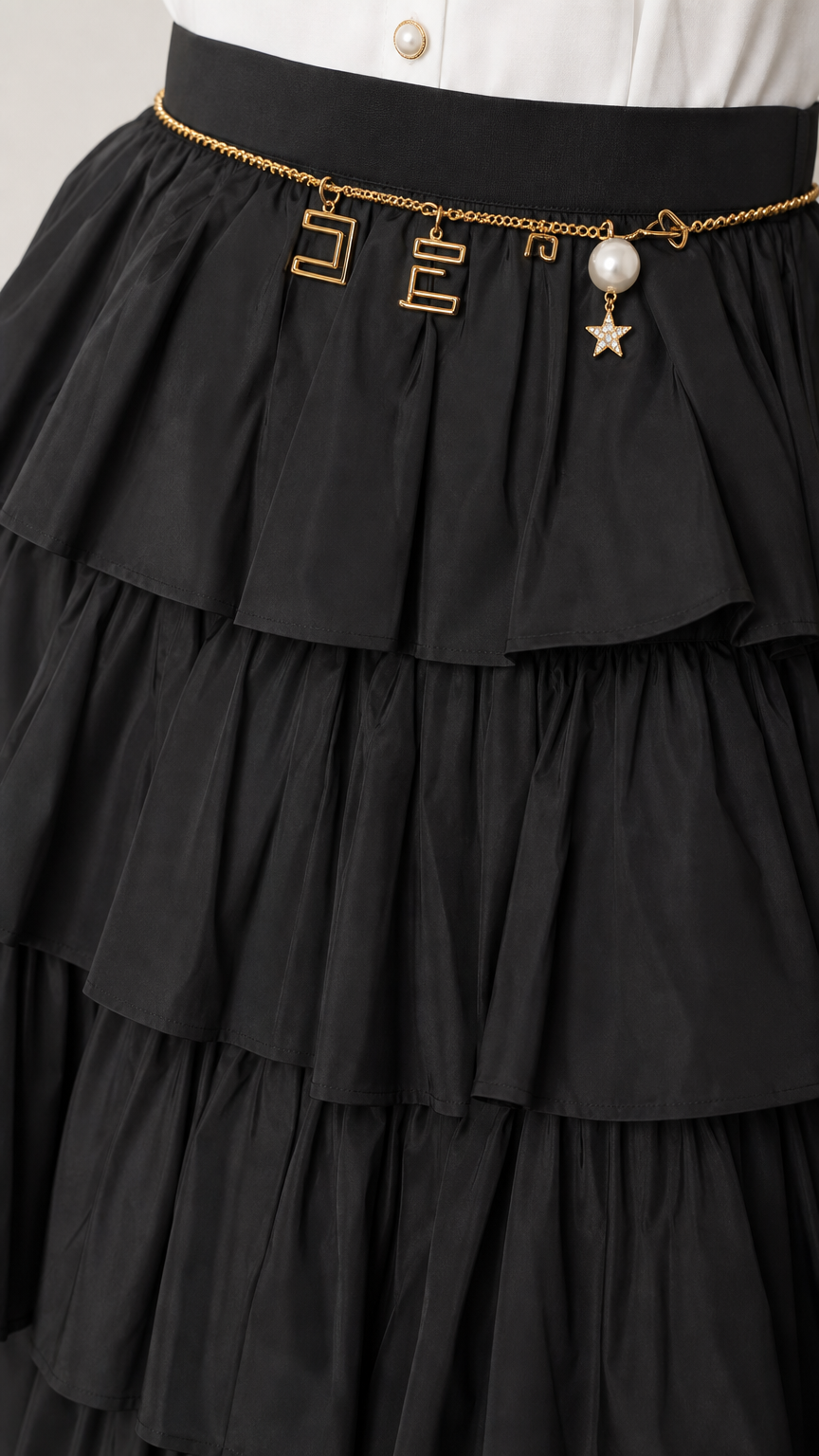 Close-up detail of the black tiered ruffles and chain belt accessory