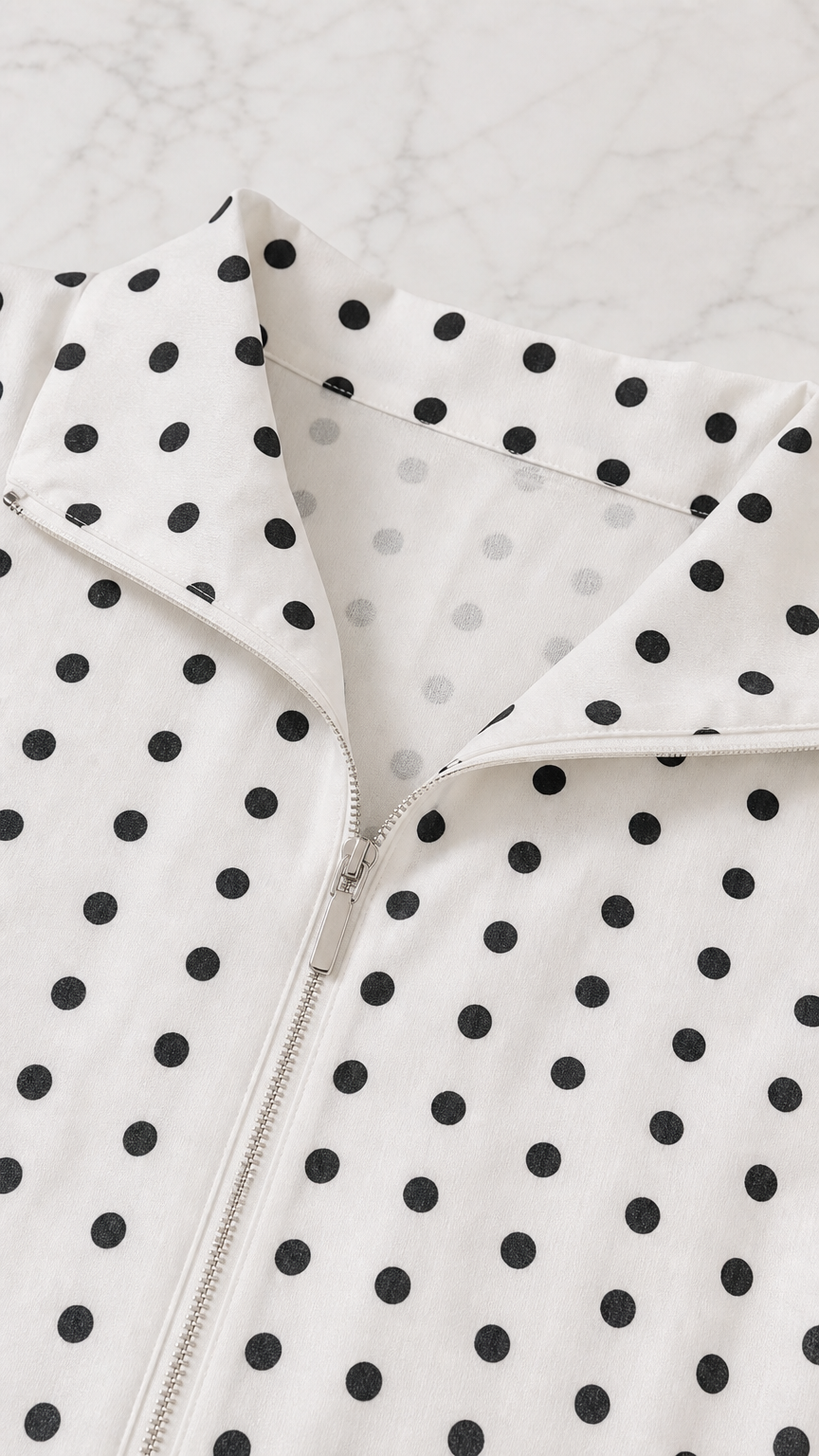 Close-up detail of the spread collar and front zipper on the polka dot top
