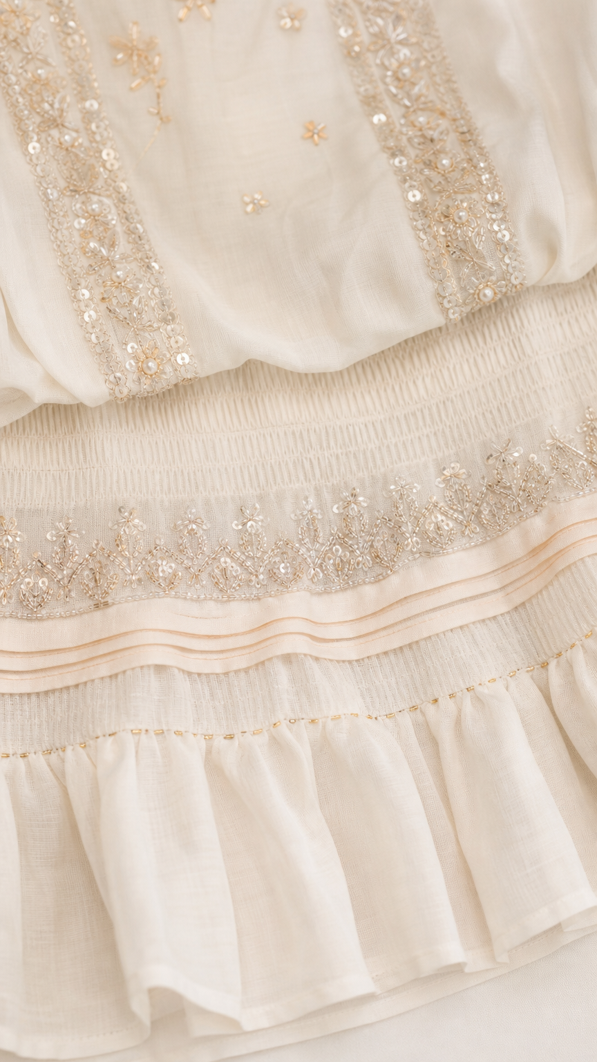 Close-up of metallic embroidery and ruffle hem details on white romper