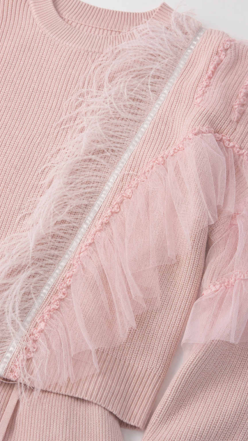 Close-up detail of soft knit texture, feather fringe, and tulle trim embellishment