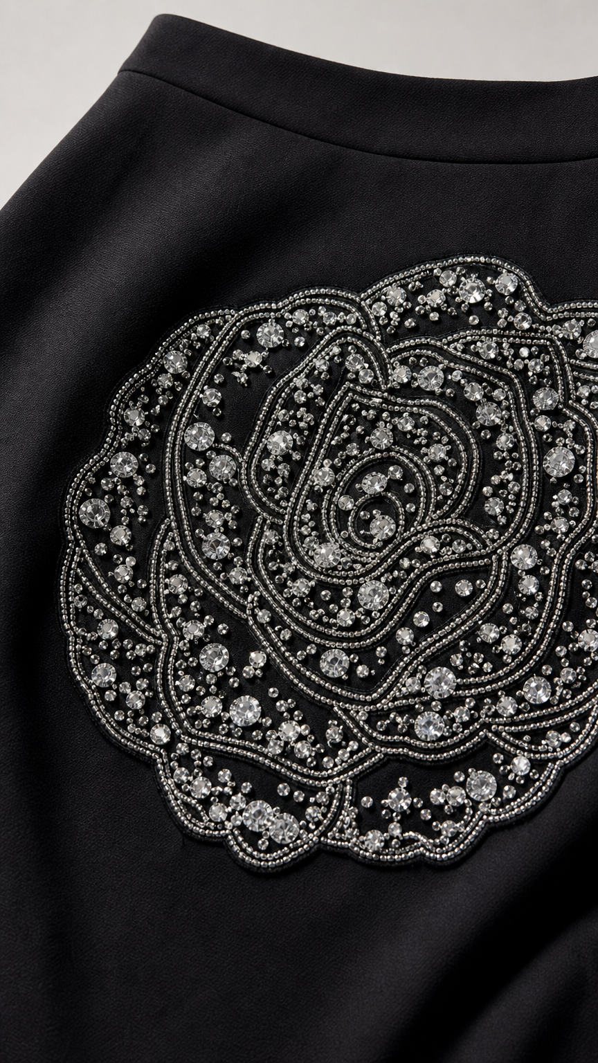 Close-up of intricate rhinestone and bead rose applique on black skirt
