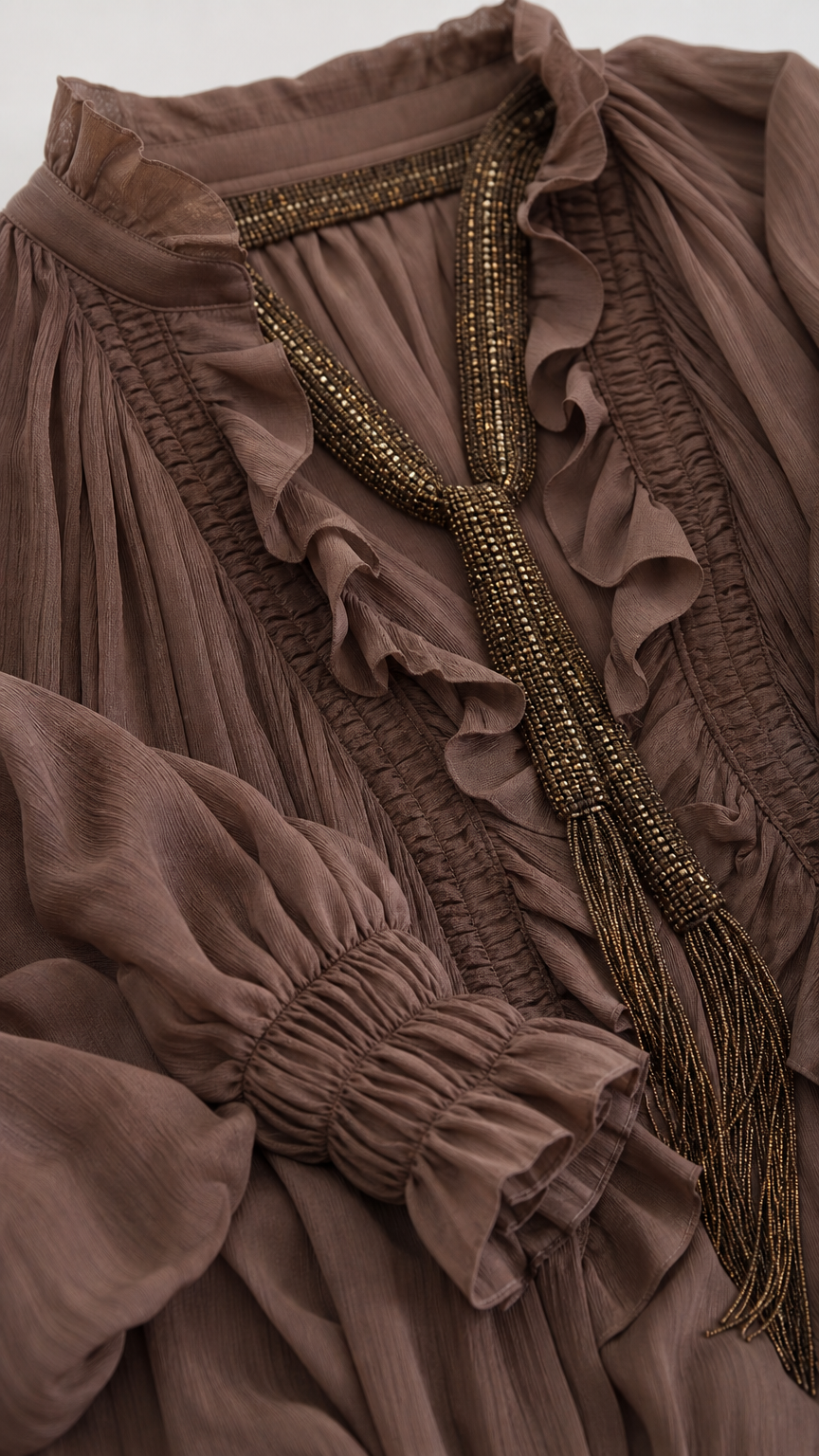 Close-up detail of ruffle neckline, textured fabric, and beaded neck ties on boho blouse
