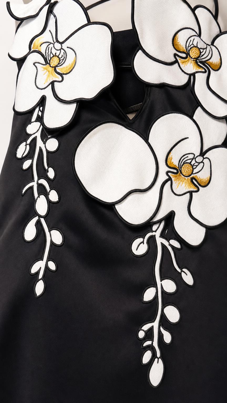 Close-up detail of the 3D white and yellow floral appliques on the black dress bodice