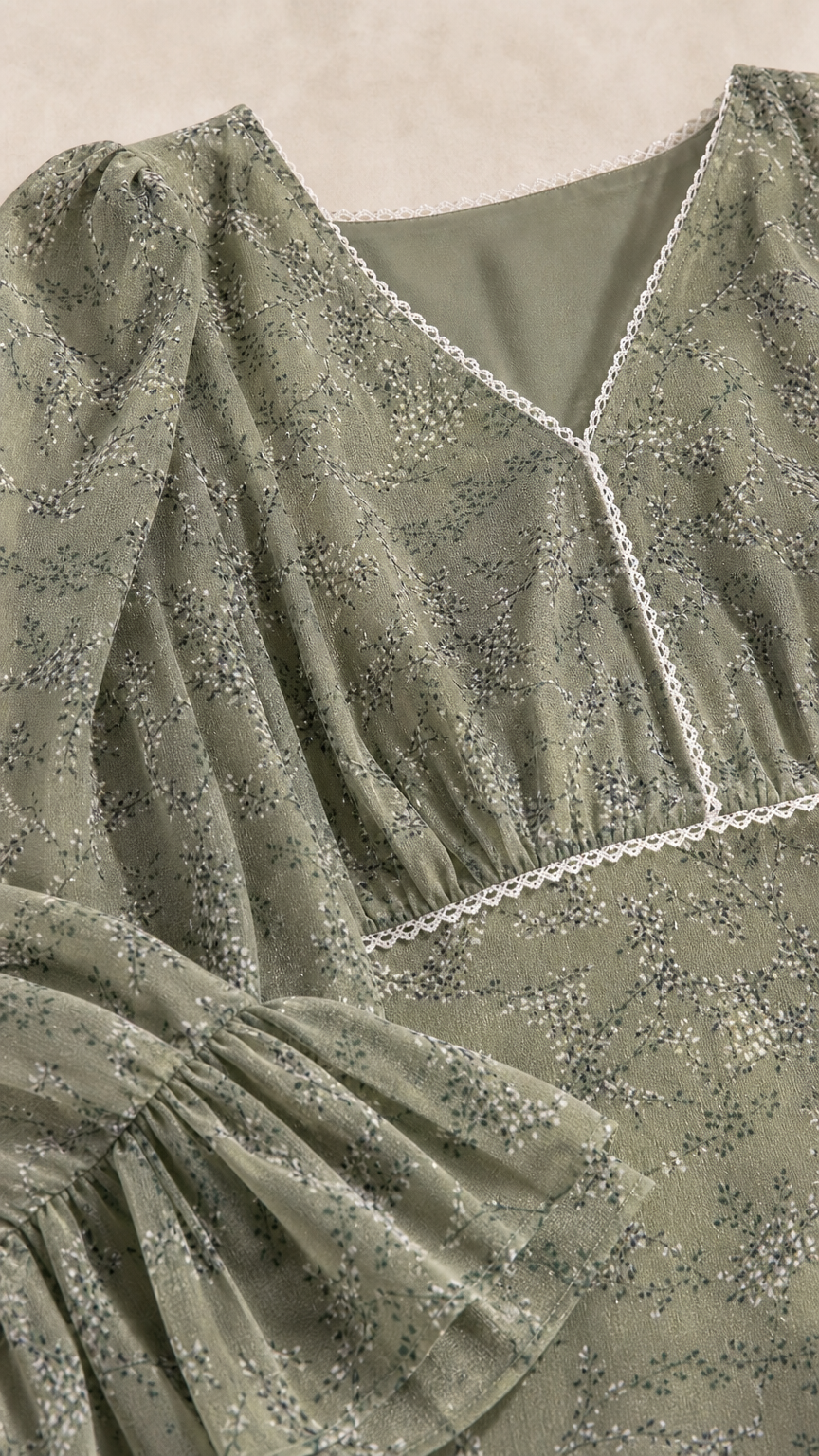 Close-up of sage green floral print fabric with lace V-neckline and ruffled sleeve detail