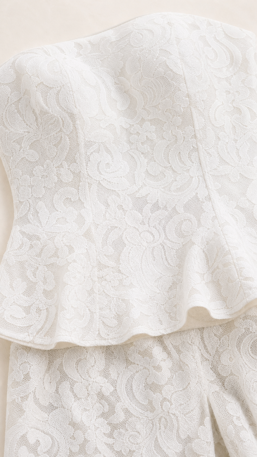 Close-up detail of white floral lace texture and peplum hem