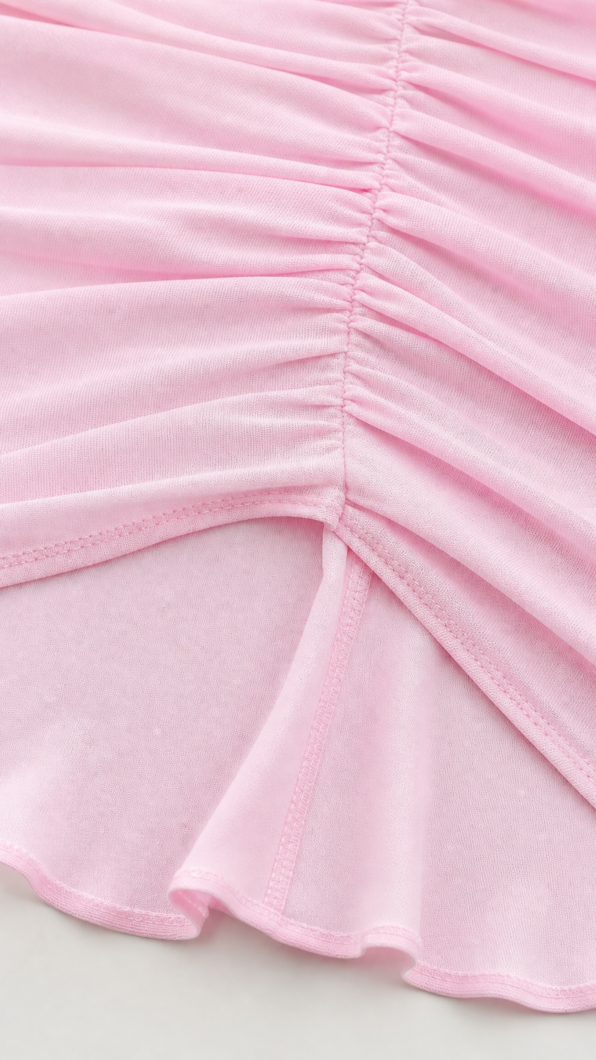Close-up detail of ruching and hemline on pink dress