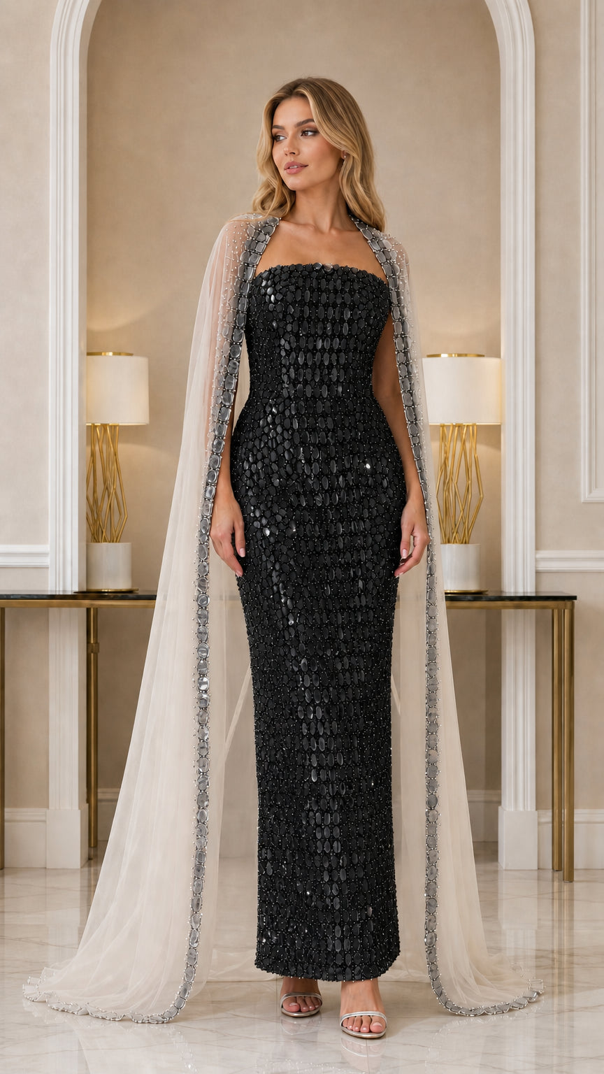 Model wearing Black strapless beaded column gown with sheer cape