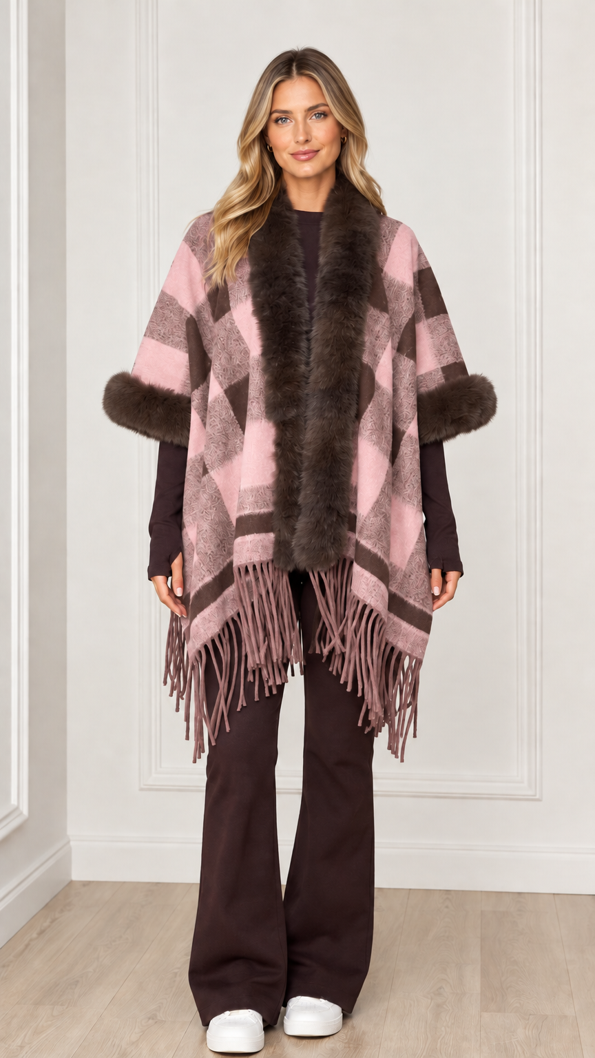 Woman wearing dusty pink plaid poncho wrap with faux fur trim and fringe