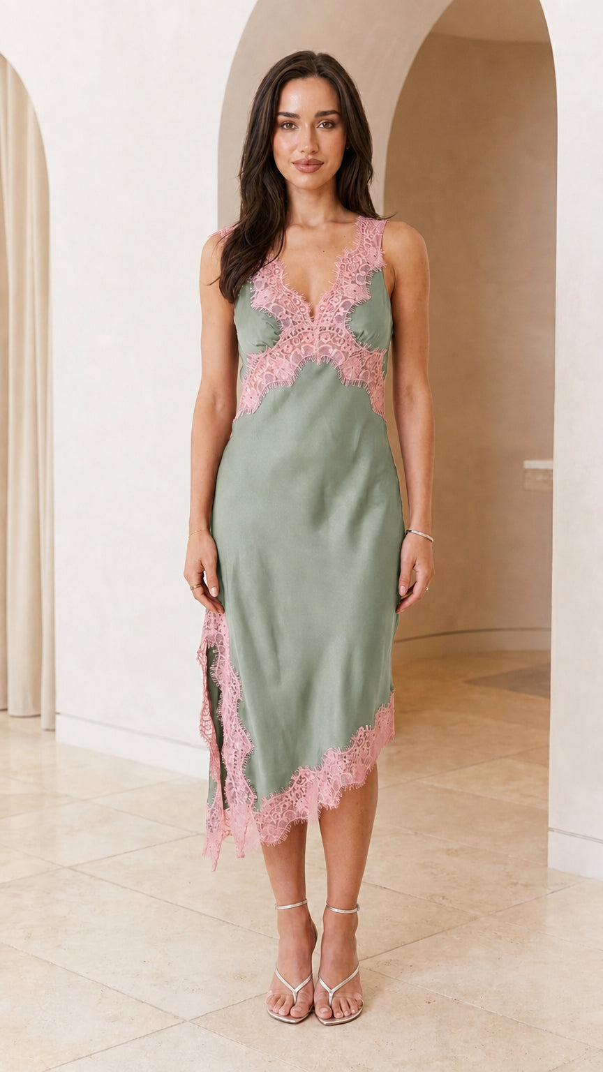 Front view of woman wearing sage green satin midi slip dress with pink lace trim