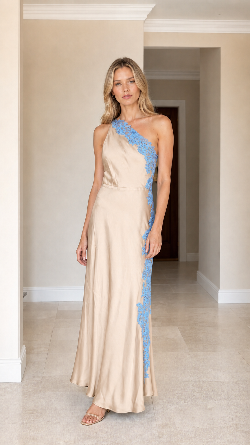 Front view of woman wearing champagne one-shoulder satin maxi dress with blue lace applique
